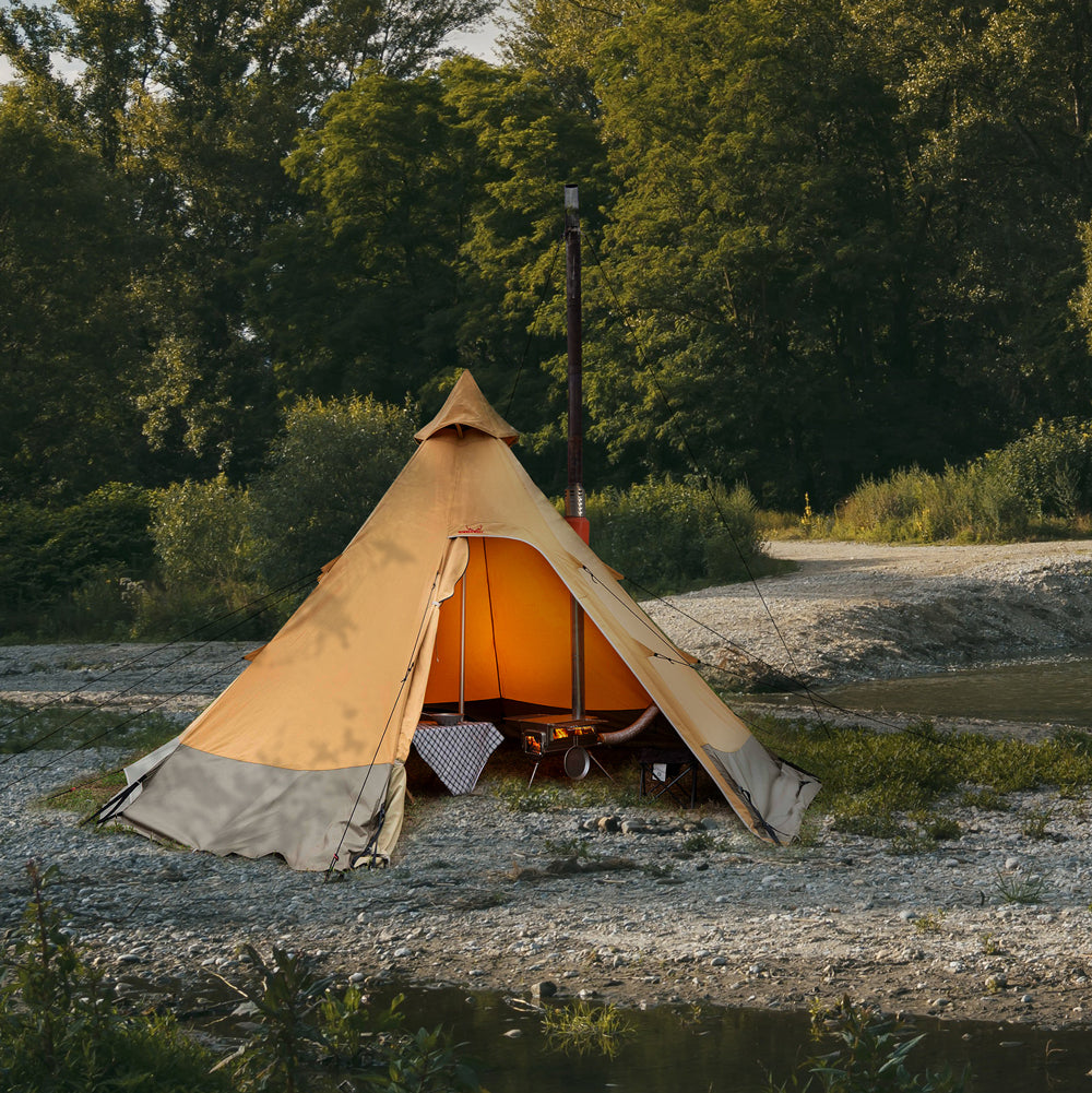 A tent with an orange interior set up in a natural outdoor environment, surrounded by trees and open space.