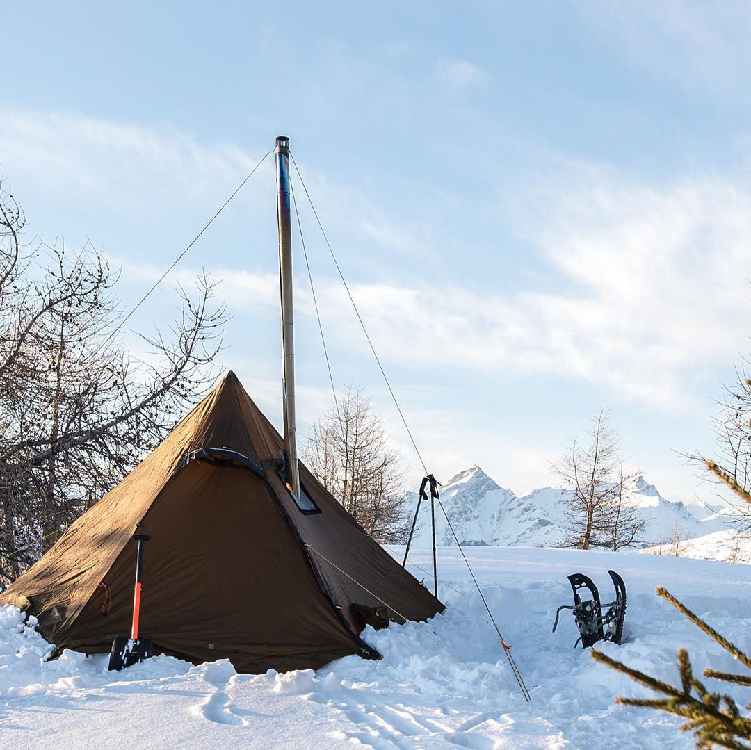 Winnerwell® guyline pegs and cord used to secure a tent in a snowy outdoor environment, demonstrating their practical application for stable camping setups.