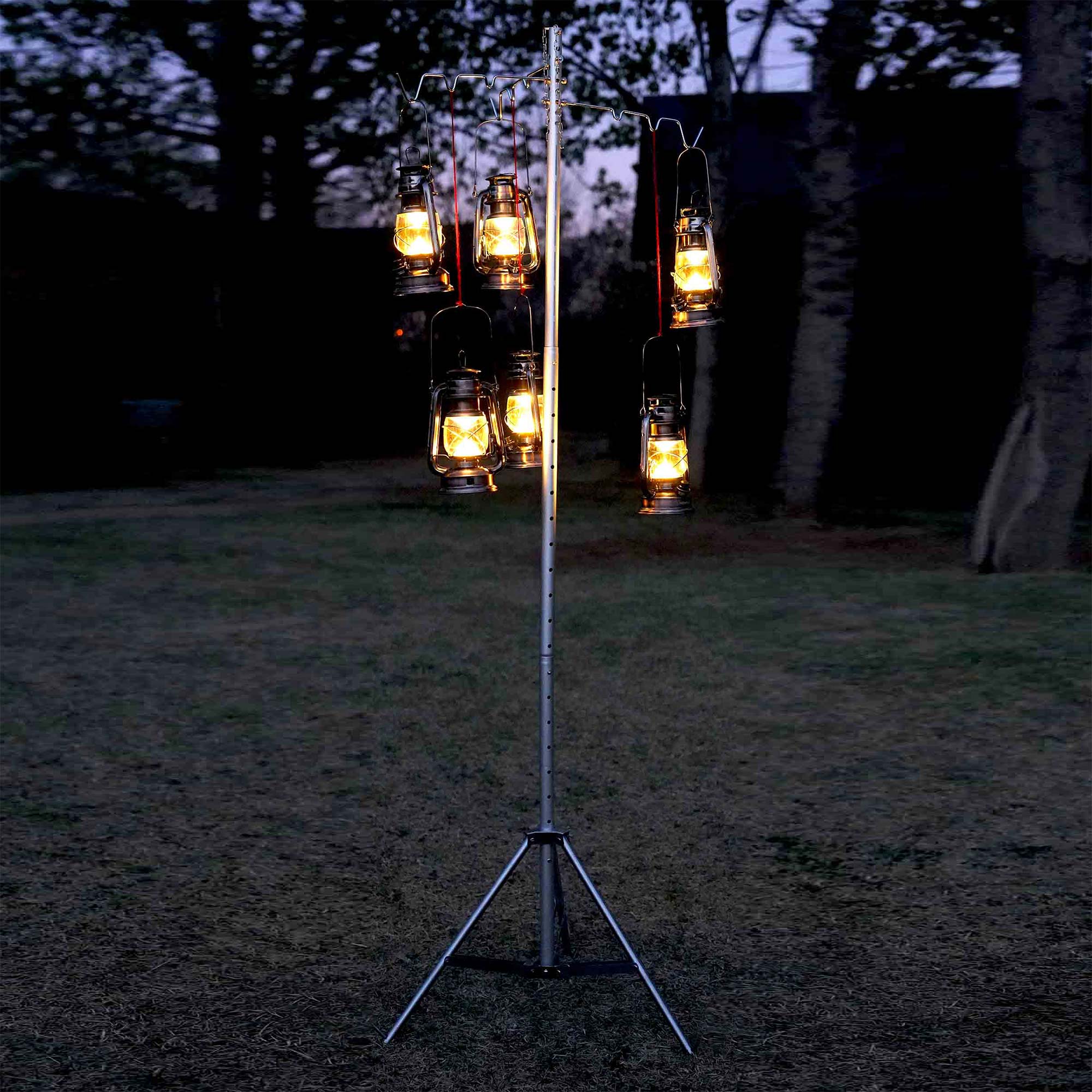 Winnerwell® Lantern & Pipe Stand set up outdoors at night, with lanterns hanging from it, creating a warm ambiance in a natural environment.