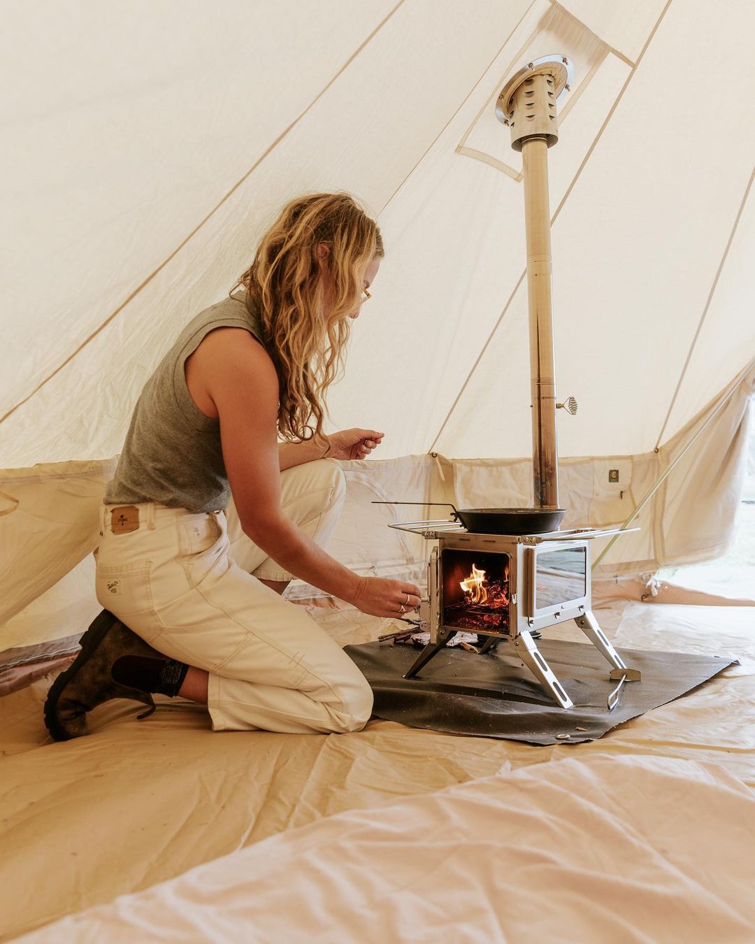 Stainless steel wood stove Winnerwell Nomad View cooking coffee on a camping stove inside canvas hot tent