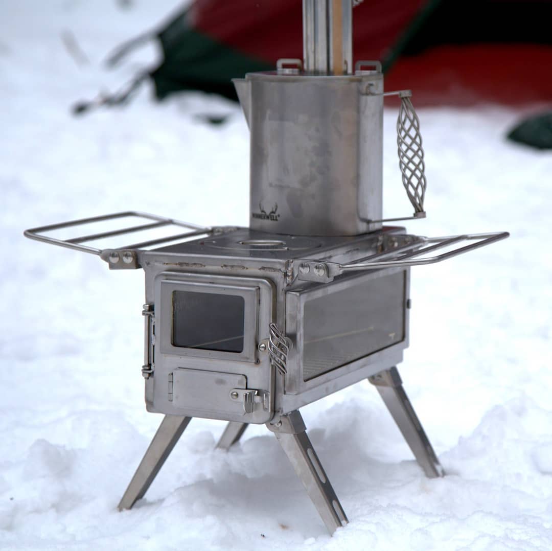 Winnerwell Nomad View portable wood stove heating a hot tent stove setup during winter camping in snowy forest