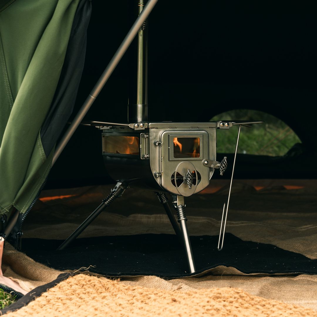 Close-up of Winnerwell® Woodlander Double View 1G Stove—double heat-resistant glass windows show flames inside, allowing safe fire monitoring during camping. Perfect for outdoor cooking and tent heating.